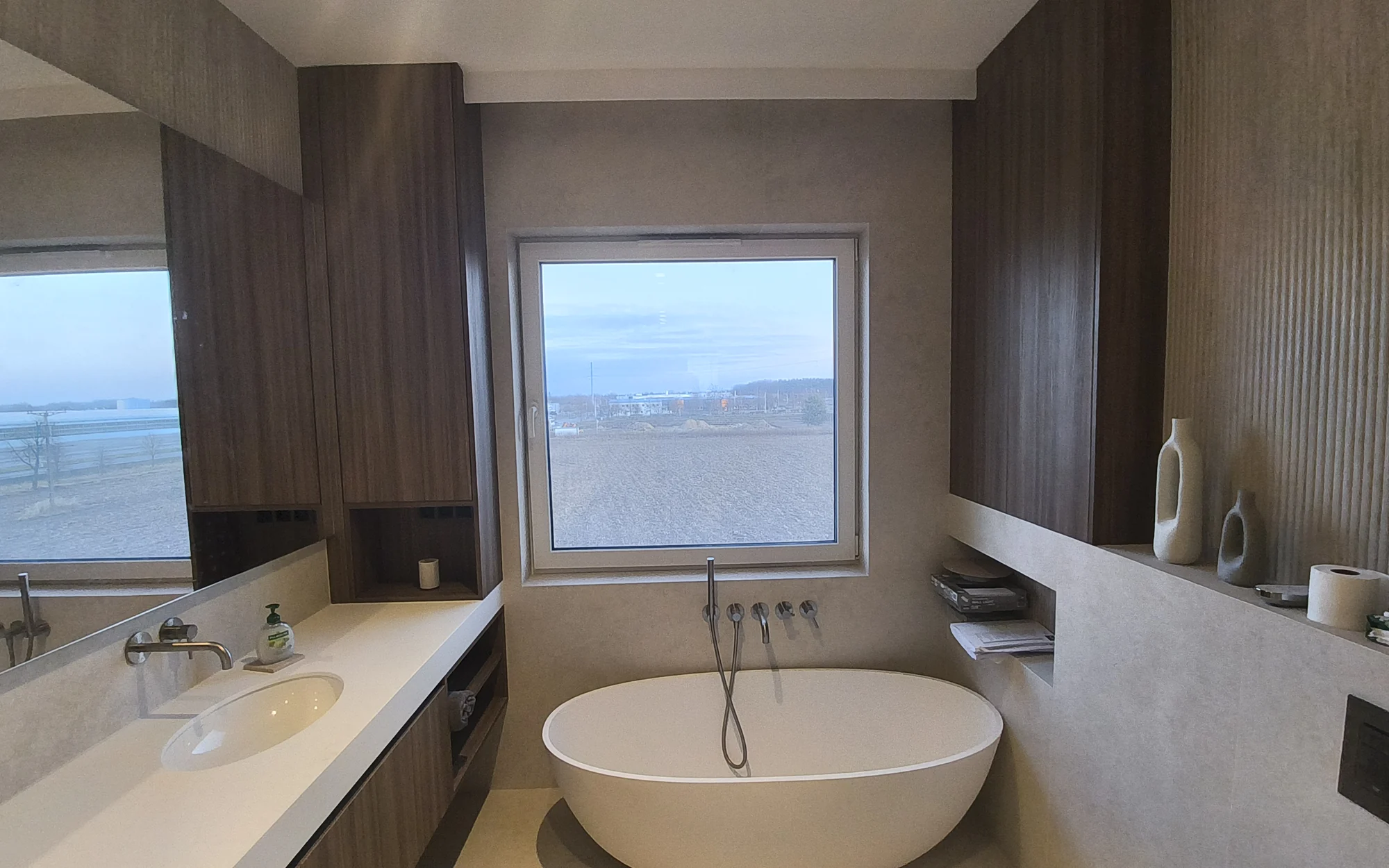 Wanna pod oknem, jasny blat i drewniana zabudowa łazienki w apartamencie w Siechnicach